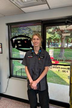 Auto shop employee standing inside office with windows.