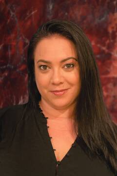 Person with black shirt and long hair, red background.