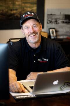 Smiling person in All Tech polo and cap.